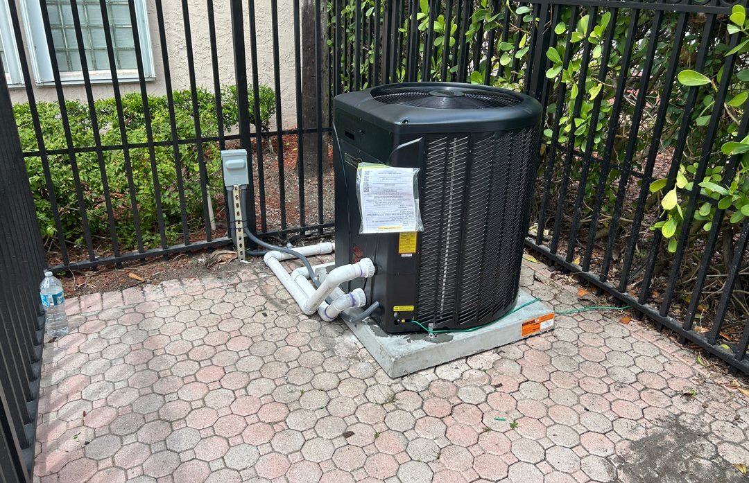 A new pool heat pump on a paver pad inside a pool fence