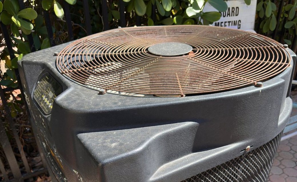 Close up of a corroded fan grill on top of a pool heat pump